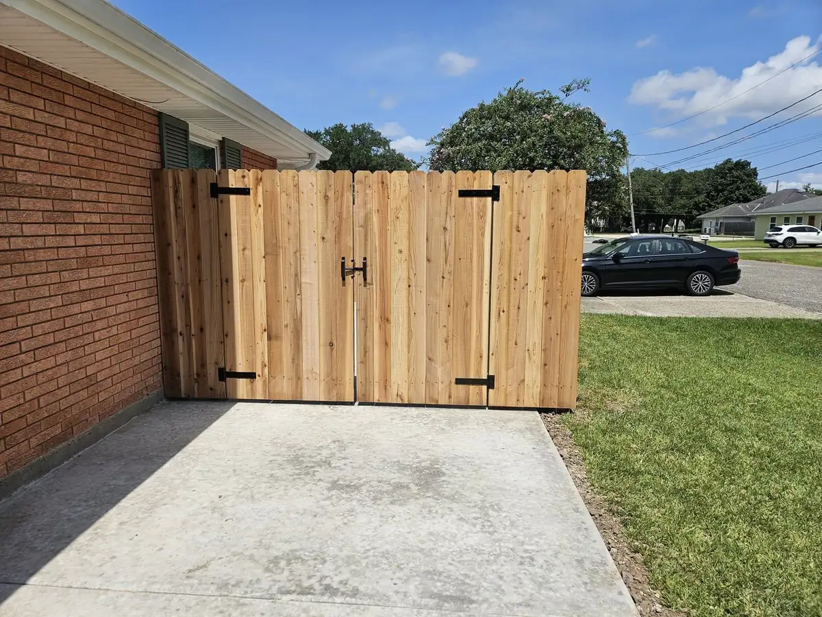 Cedar double gate with black strap hinges closing off a driveway pad