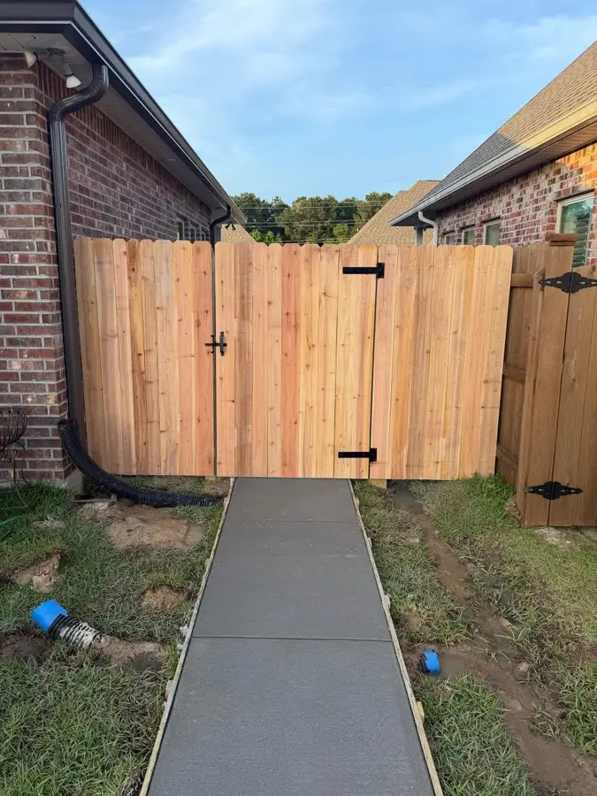New cedar fence and gate at the end of a concrete side walkway