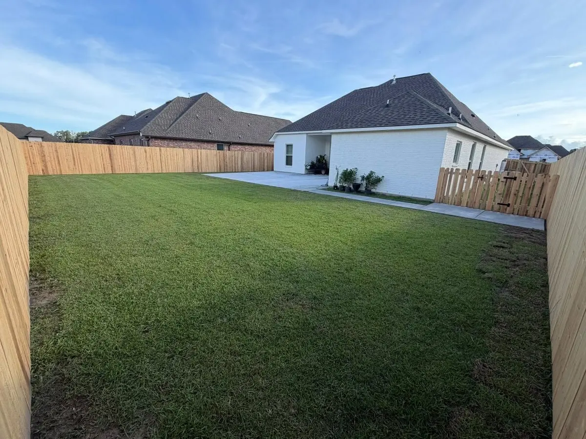 Backyard privacy fence with a shorter picket section and gate near the house