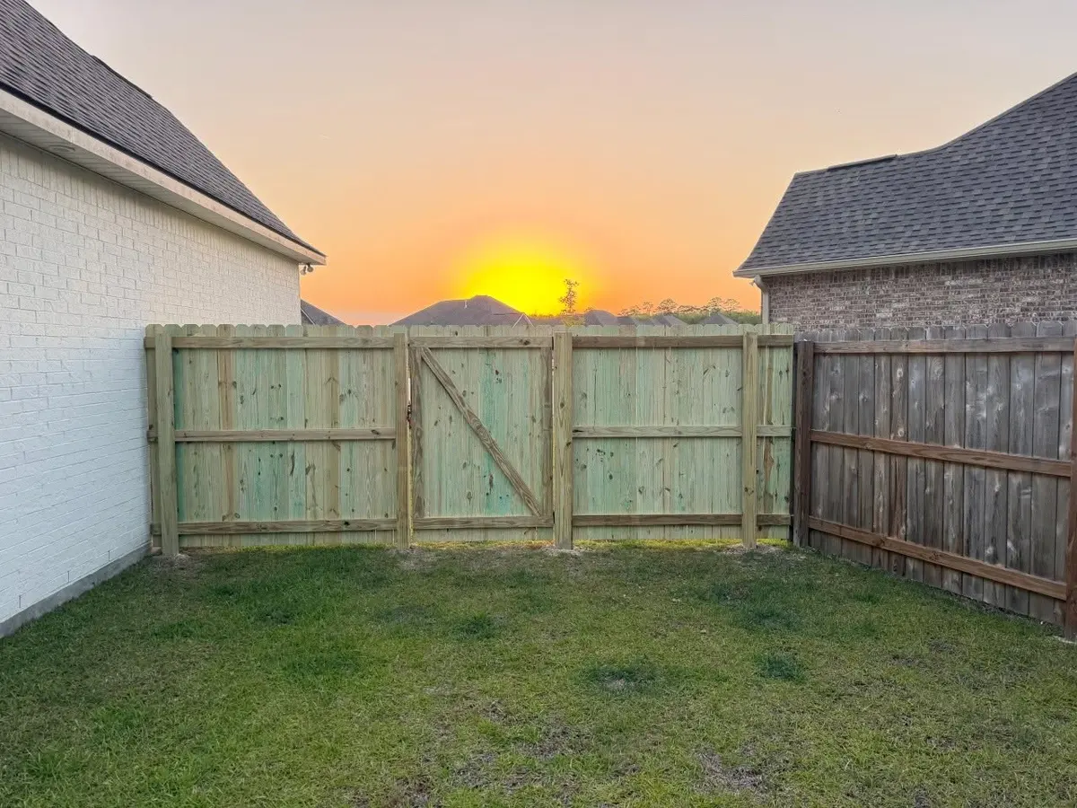 Inside of a new pressure-treated pine fence and gate at sunset