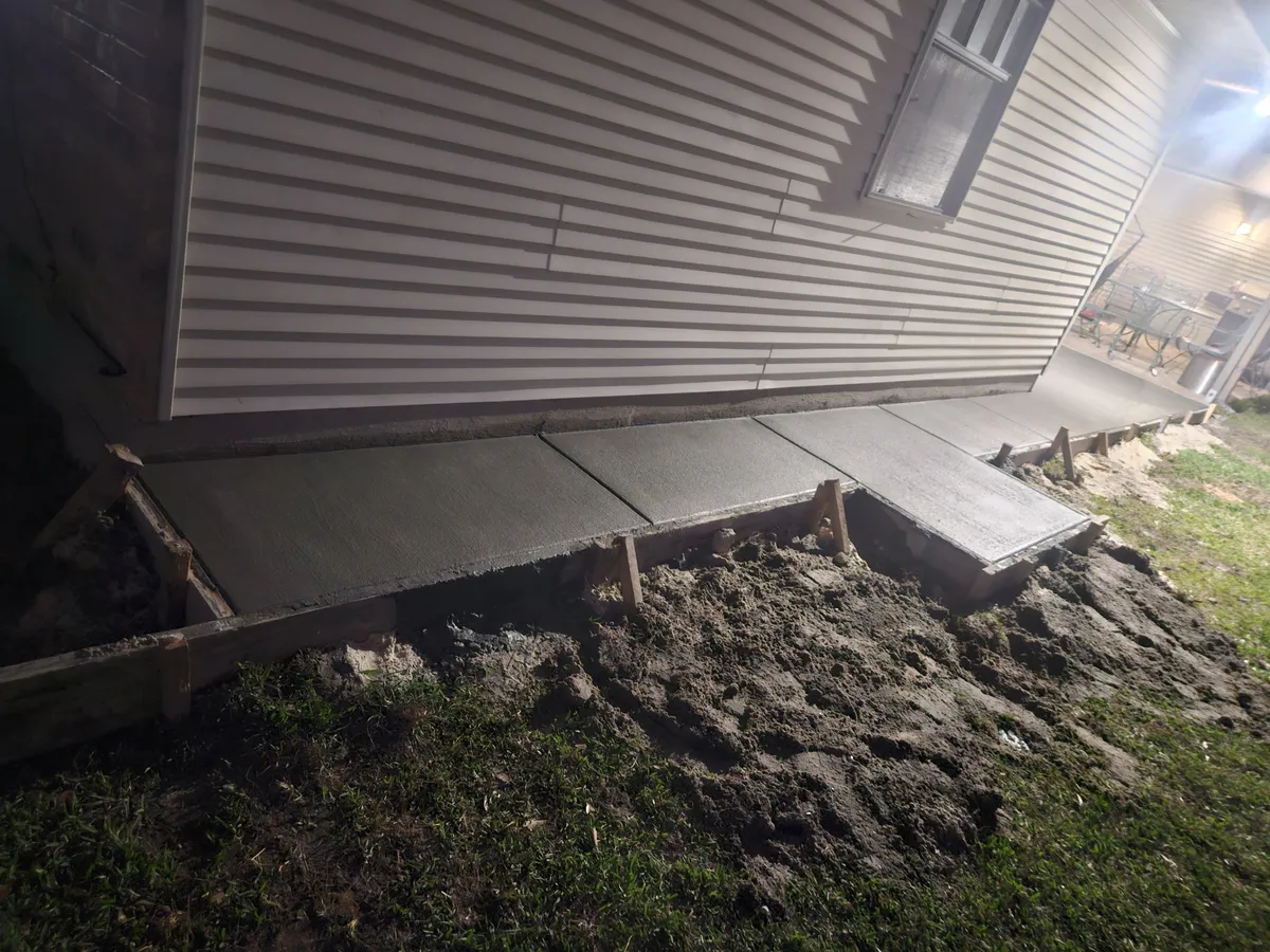 Fresh concrete sidewalk and steps poured next to house