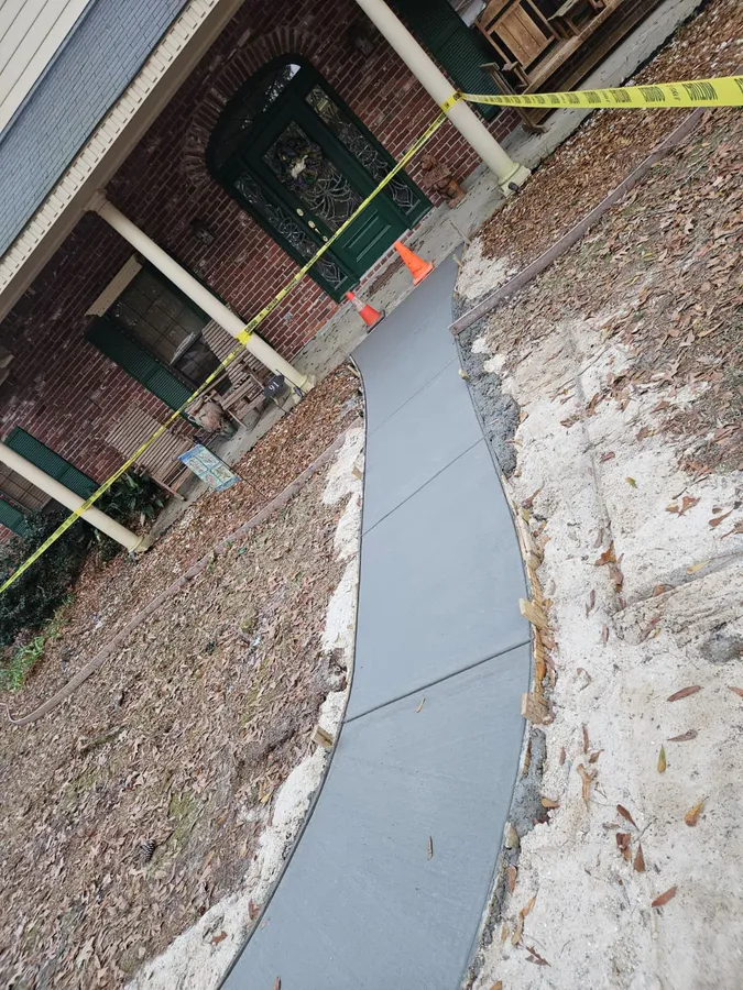 Fresh concrete sidewalk with safety cones along home entryway